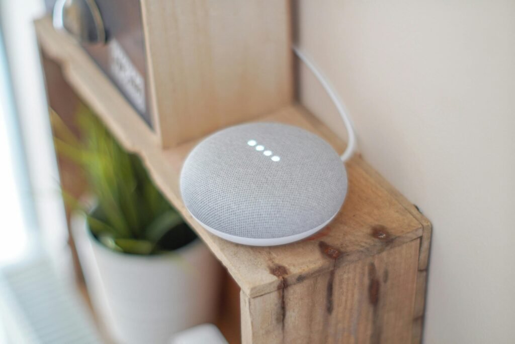 pexels photo 1072851 1072851 A Google Home Mini smart speaker on a wooden shelf, blending technology with home decor.